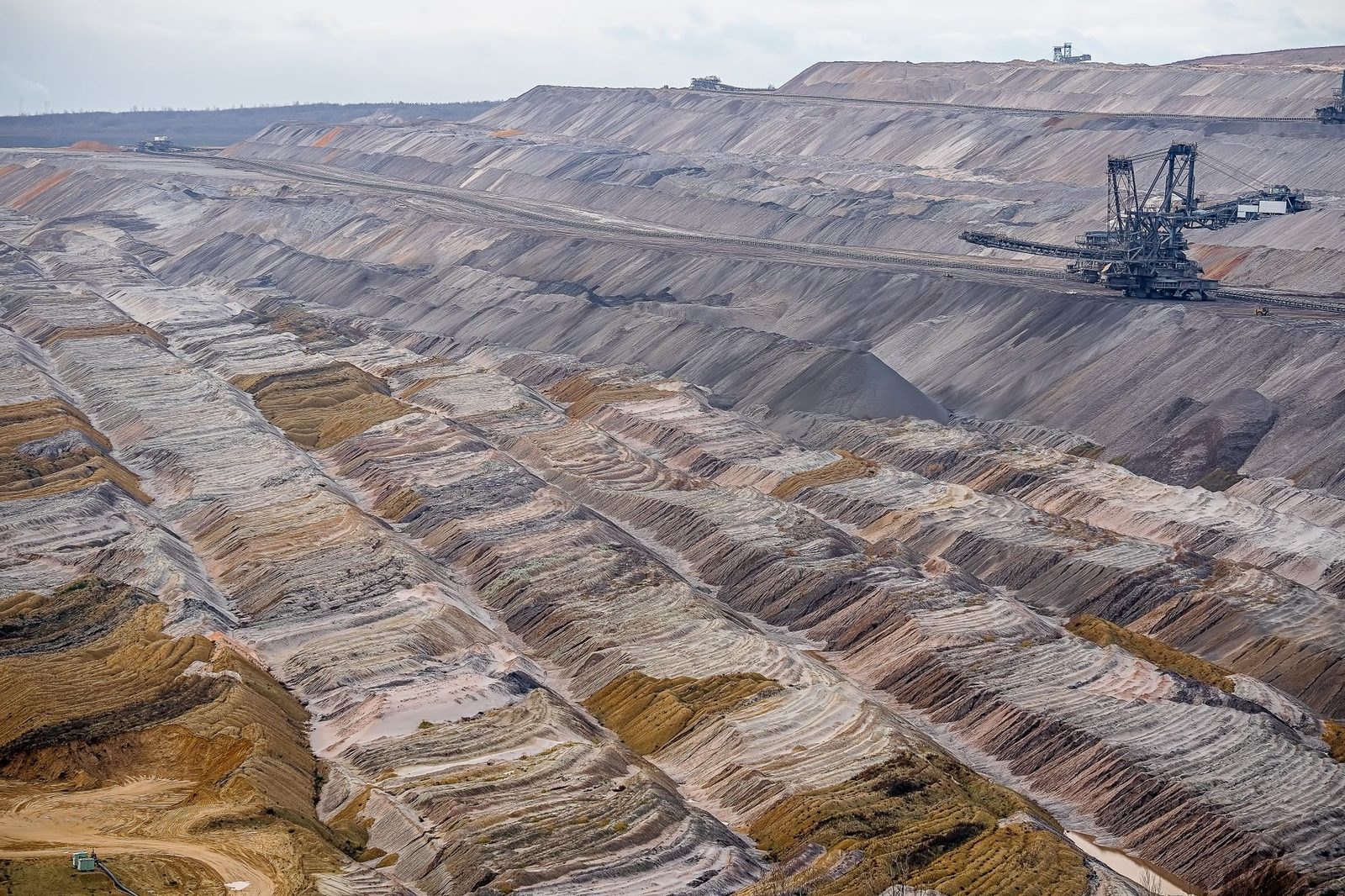 Mina a cielo abierto con terrazas escalonadas y una gran excavadora al fondo